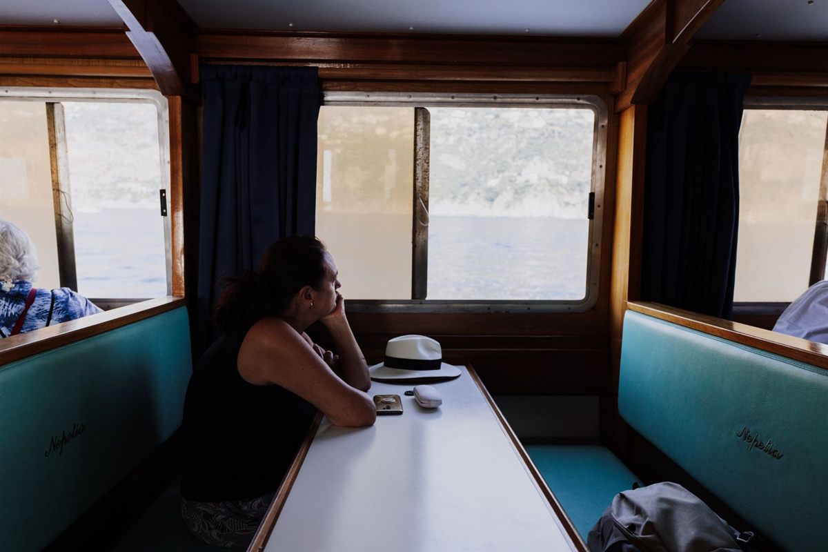 A traveller gazing out of a ship’s window from a booth seat