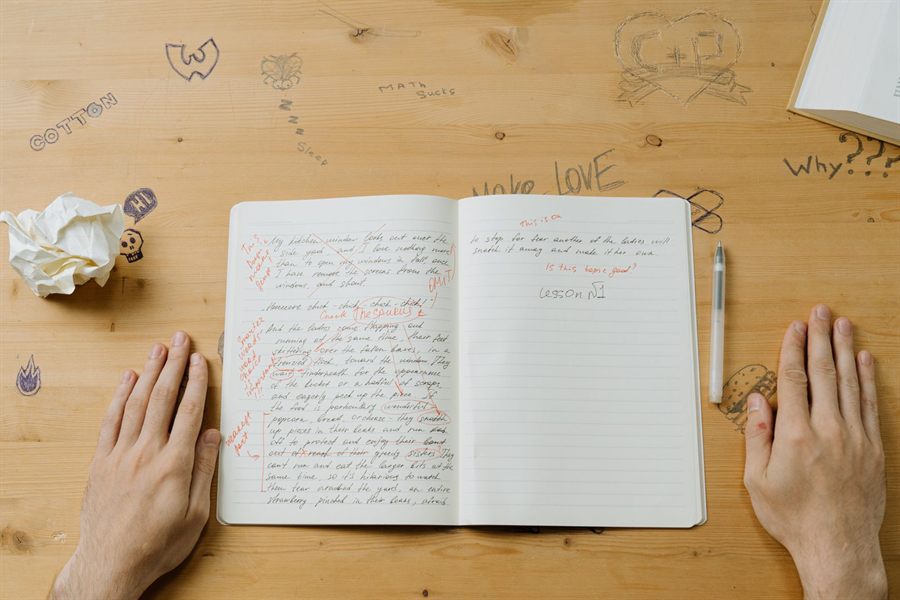 Hands resting beside an open notebook full of handwritten notes